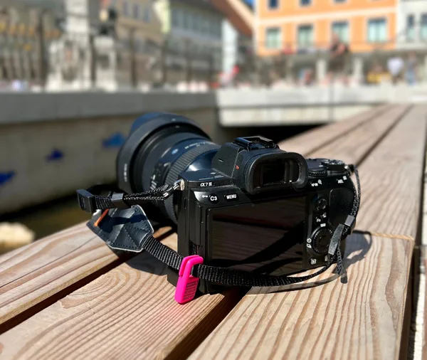 A camera with a pink Premium QR Tag on its strap